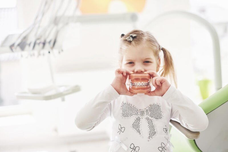 a little girl in the dentists office holds a model GN67MHE 1 e1733706042658 Mason Dentistry Blog